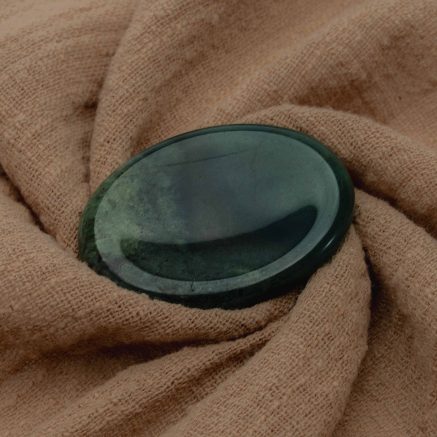 Polished Moss Agate incense cone stand in deep green tones, displayed on soft beige fabric