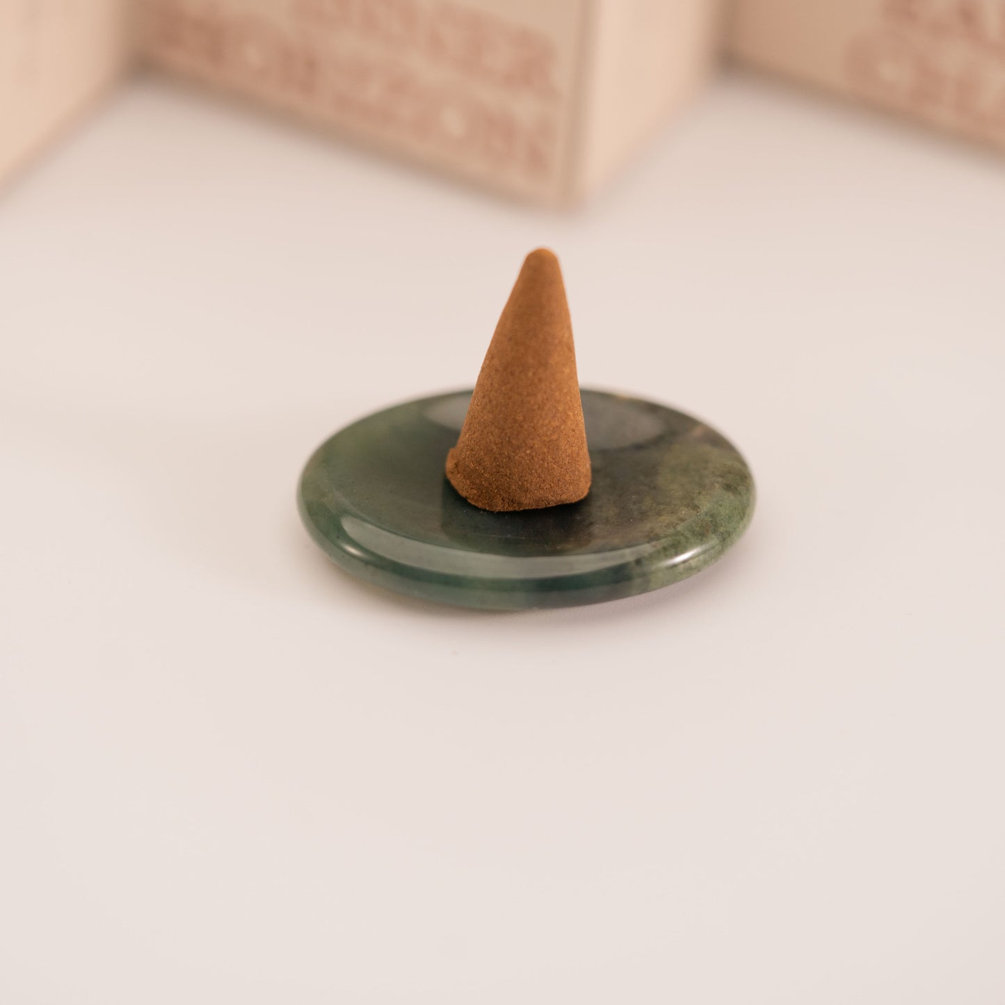 Brown incense cone placed on a polished green Moss Agate stand