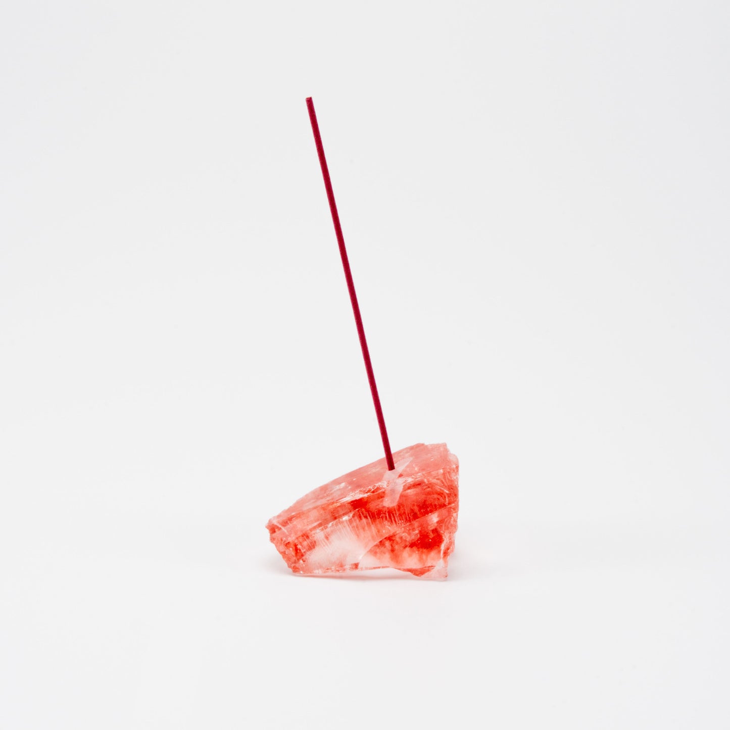 Glossy red fused stone incense holder with a single upright incense stick