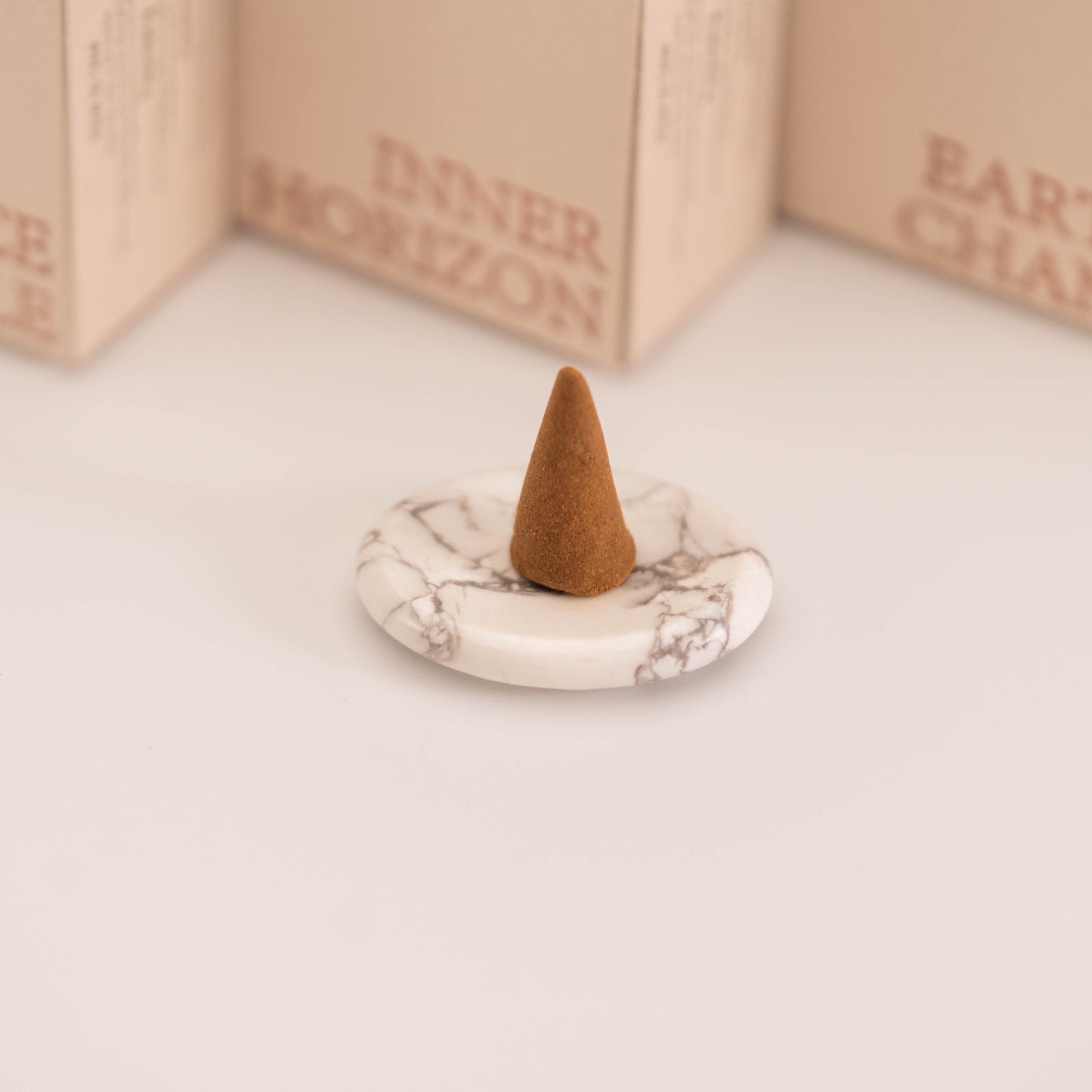 Brown incense cone placed on a polished White Howlite stand