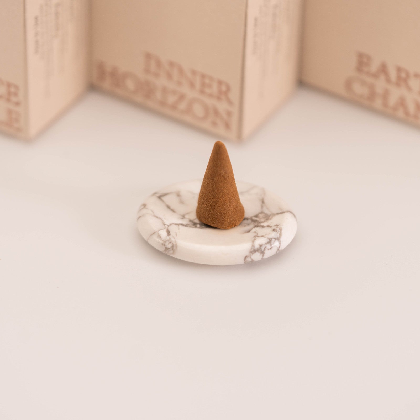 Brown incense cone placed on a polished White Howlite stand