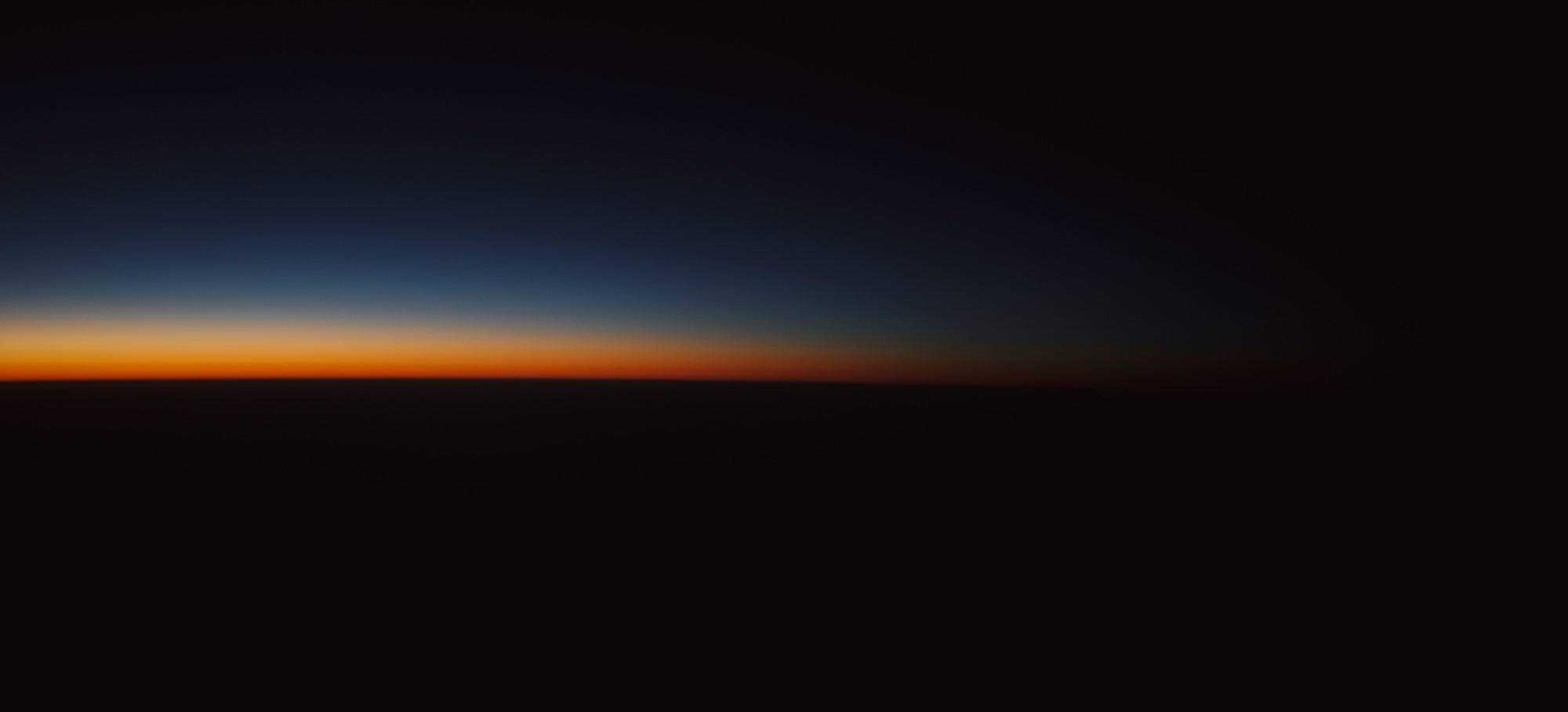 Gradient of a tranquil sunrise or sunset sky over a dark horizon