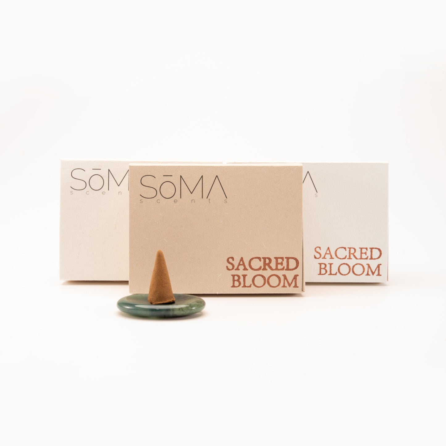 SomaScents incense cone with eco-friendly packaging in beige and white, displayed on a polished green gemstone holder against a clean white background.