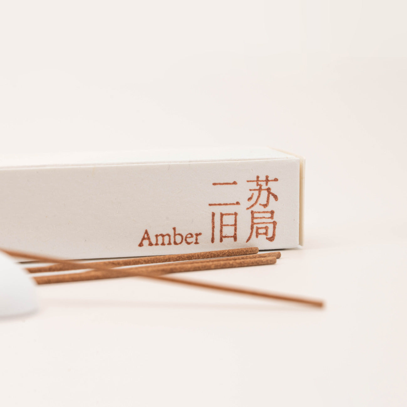 Close-up of SomaScents Amber incense sticks, displayed on minimalist packaging with a soft, neutral background.