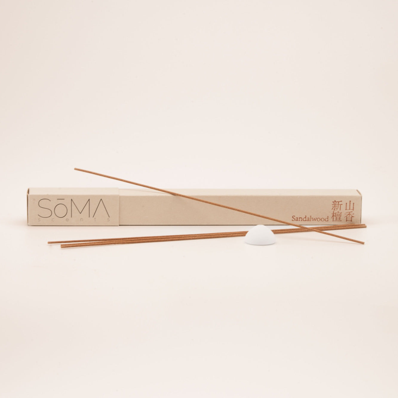 SomaScents Sandalwood incense sticks with beige packaging, red Chinese and English text, and a white ceramic holder on a soft neutral background.