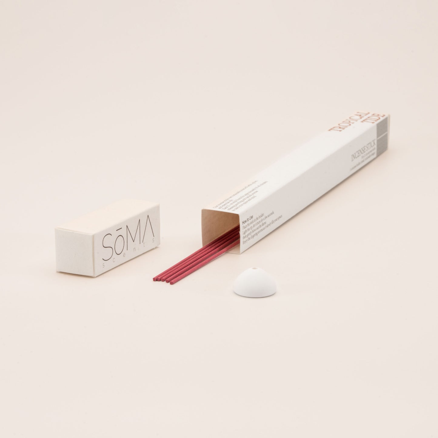 SomaScents Tropical Tide incense sticks in white minimalist packaging, displayed with red incense sticks and a small white ceramic holder
