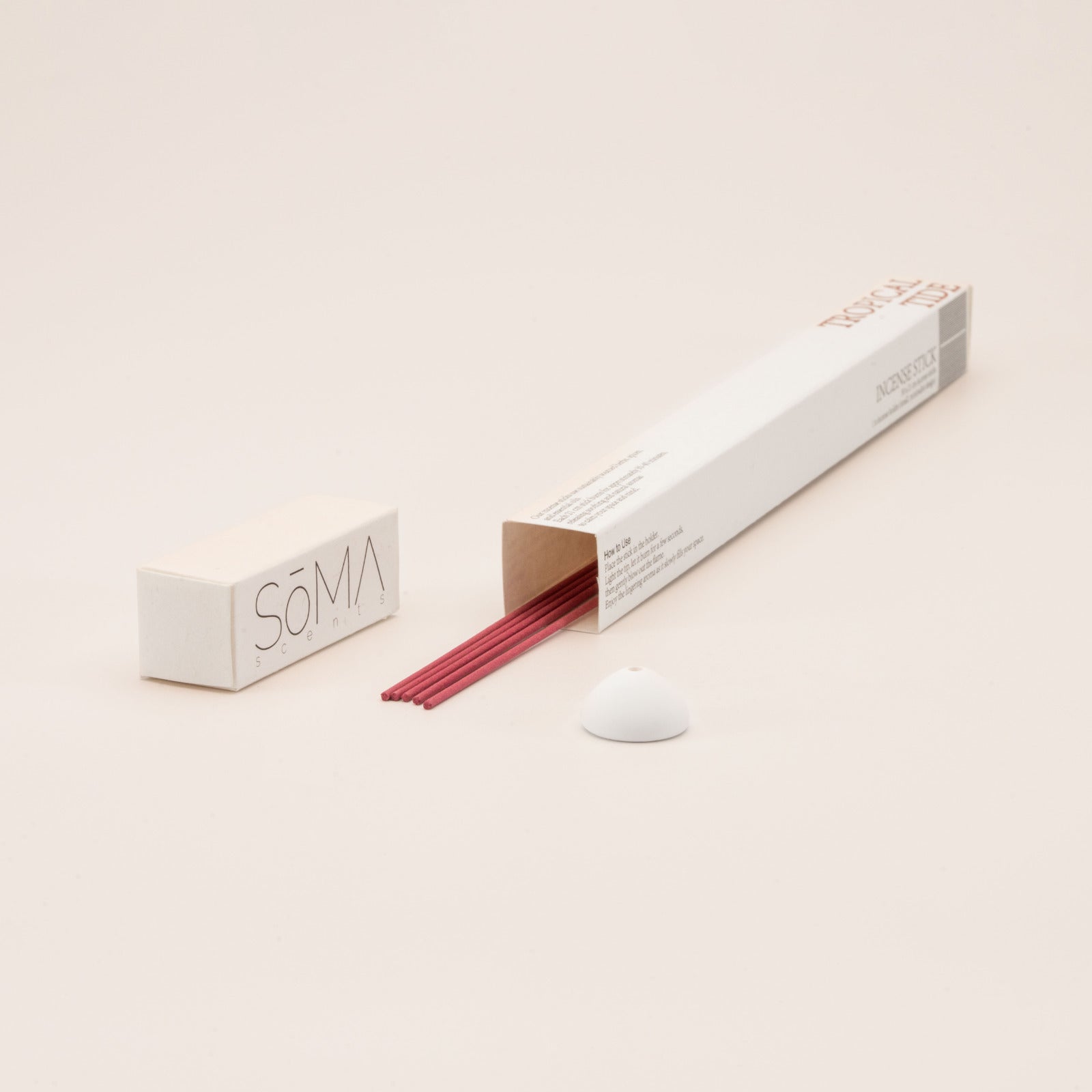 SomaScents Tropical Tide incense sticks in white minimalist packaging, displayed with red incense sticks and a small white ceramic holder