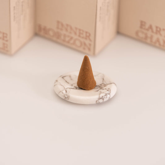 Brown incense cone placed on a polished White Howlite stand