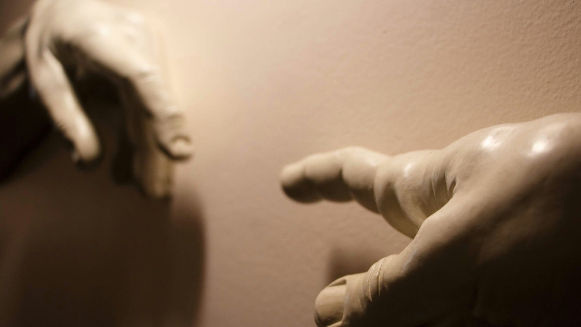 Close-up of two sculpted hands reaching toward each other