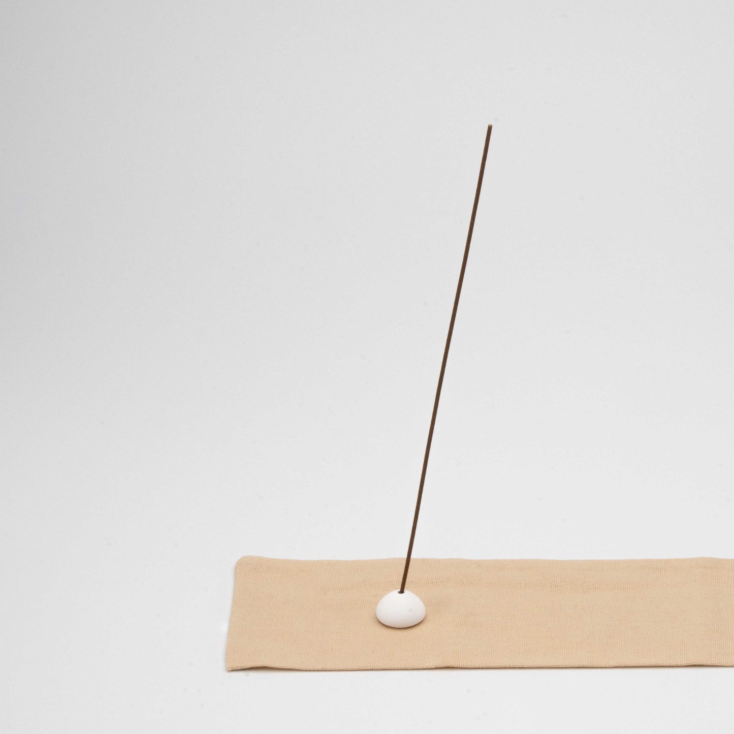 Close-up of textured cotton fabric with a stitched edge, showing detail of the beige incense mat and ceramic holder.