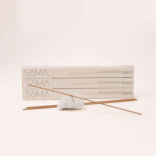 SomaScents incense stick burning in a marble-style sodalite gemstone holder, displayed in front of three stacked white incense boxes
