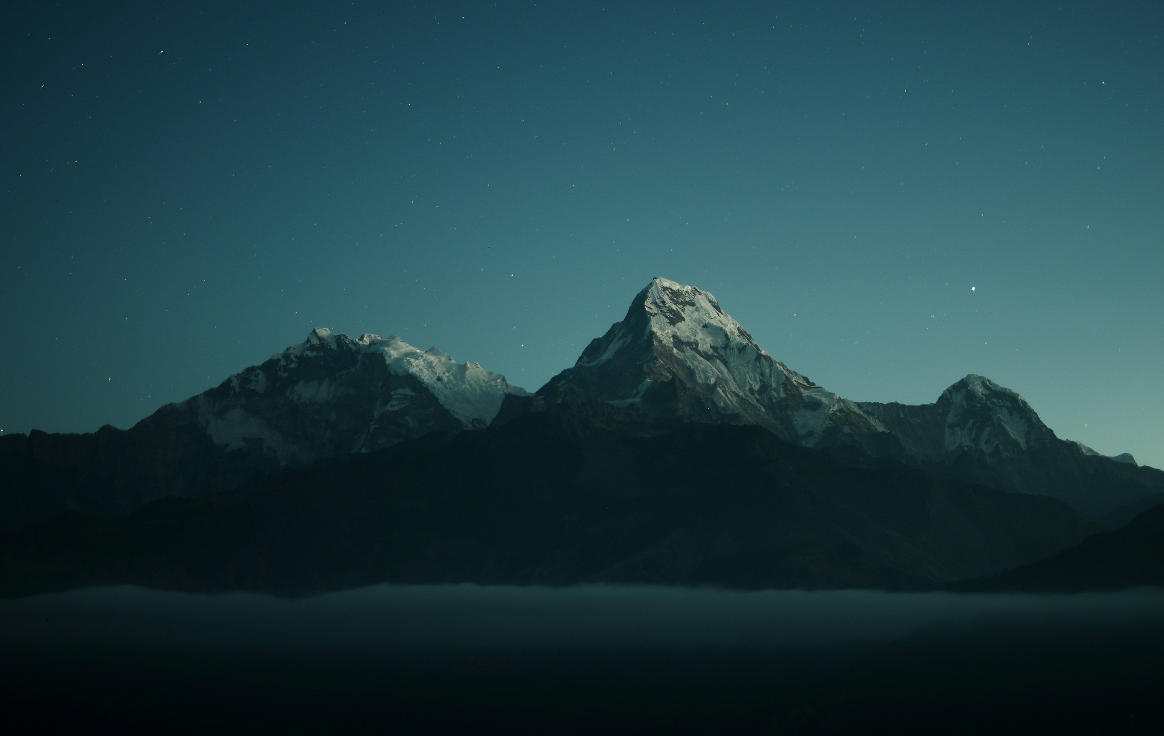 Snowy mountain peaks under a starry night sky