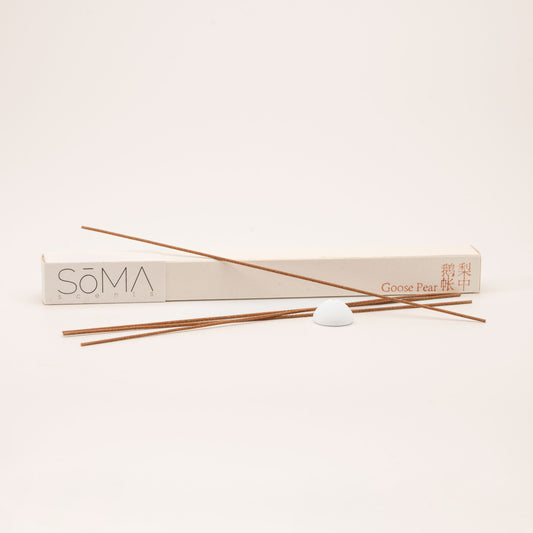 SomaScents Goose Pear incense sticks with beige packaging, red Chinese and English text, and a white ceramic holder on a soft neutral background.