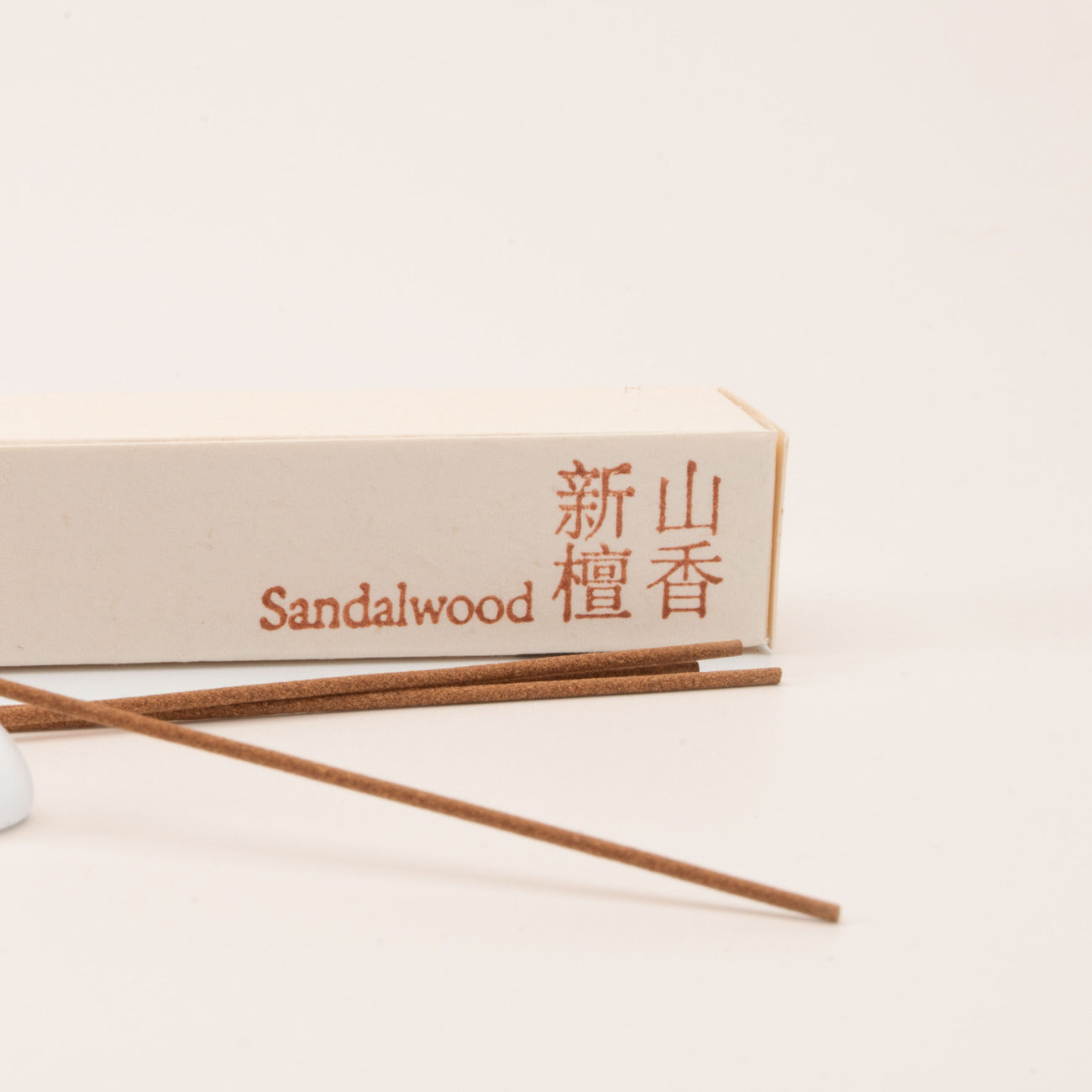 Close-up of SomaScents Sandalwood incense sticks, displayed on minimalist packaging with a soft, neutral background.