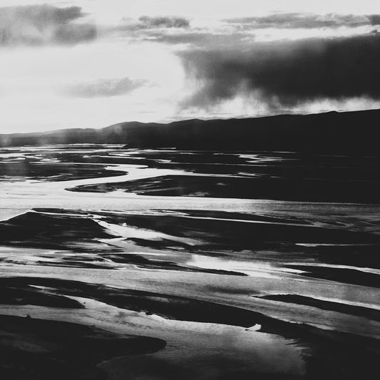 Vast river delta reflecting light under dramatic stormy skies.