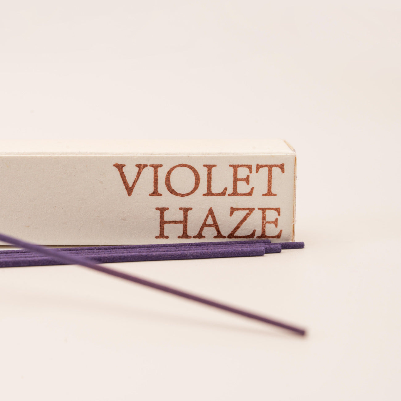 Close-up of SomaScents Violet Haze incense sticks, displayed on minimalist packaging with a soft, neutral background.