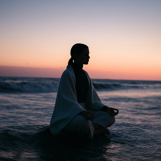 Person meditating by the ocean at sunrise in a serene posture